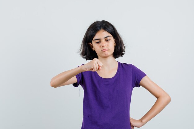 Menina olhando para o punho cerrado na camiseta e parecendo confiante,