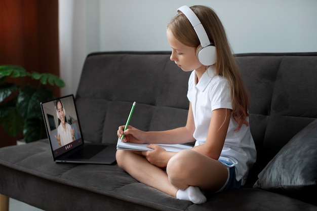 Menina participando de aulas online usando fones de ouvido