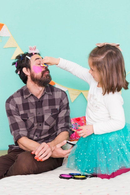 Foto grátis menina passando o tempo com o pai fazendo maquiagem