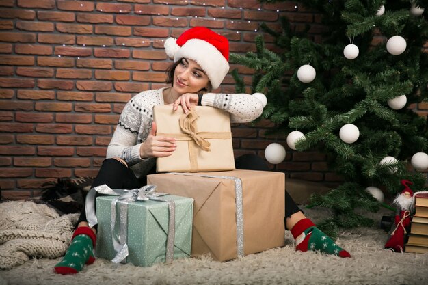 Menina pela árvore de Natal desempacotando presentes
