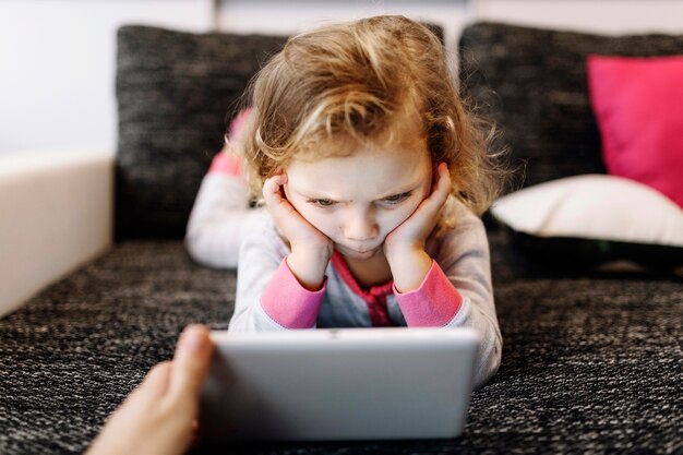 Menina pensativa assistindo vídeo no tablet