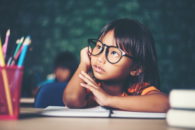 Menina pensativa com livro perto de um conselho escolar