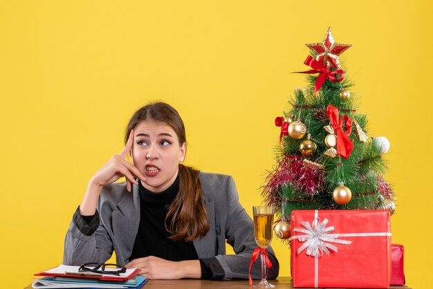 Menina pensativa de frente para a mesa, colocando a mão