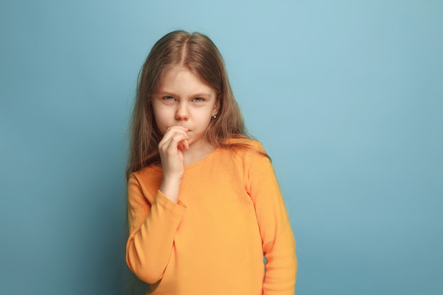 menina pensativa. menina adolescente triste em um fundo azul do estúdio. Expressões faciais e conceito de emoções de pessoas.