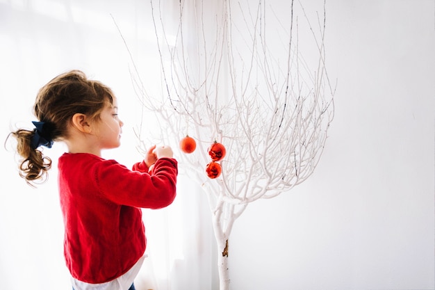 Foto grátis menina pequena que decora a árvore de natal