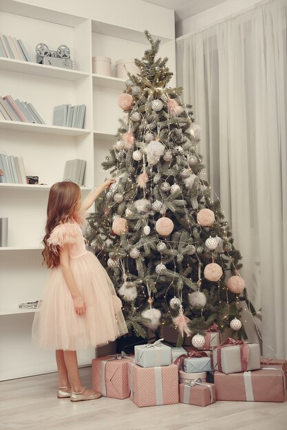 Menina perto de árvore de Natal em um vestido rosa