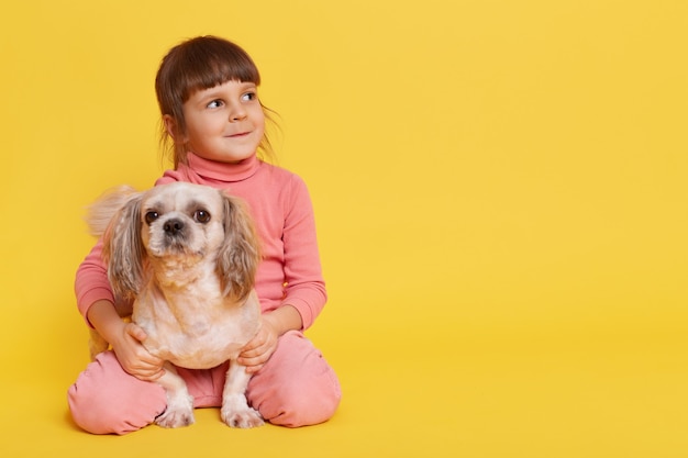 Foto grátis menina posando com cachorro pequinês em amarelo