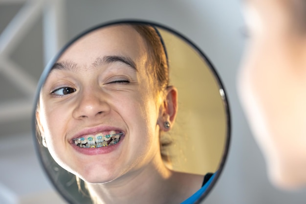 Menina pré-adolescente caucasiana com aparelho nos dentes olhando no espelho