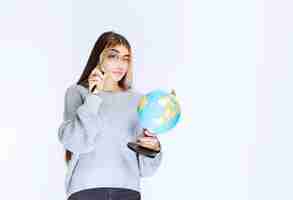 Foto grátis menina procurando locais ao redor do globo com uma lupa.