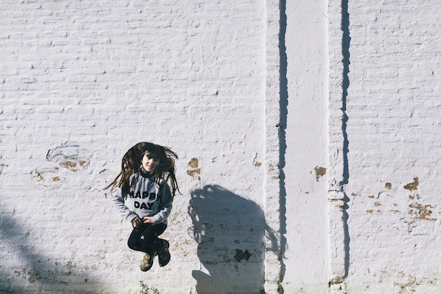 Foto grátis menina pulando perto de parede branca