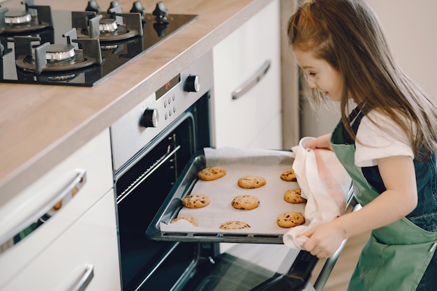 Foto grátis menina puxa uma bandeja de biscoitos do forno
