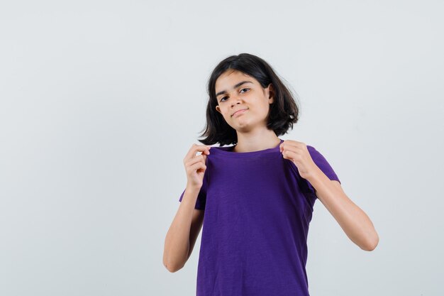 Menina puxando a gola da camiseta e parecendo orgulhosa