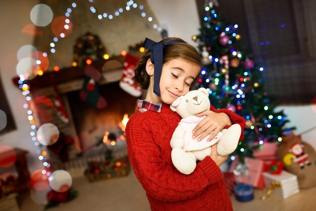 Menina que abraça um urso de peluche