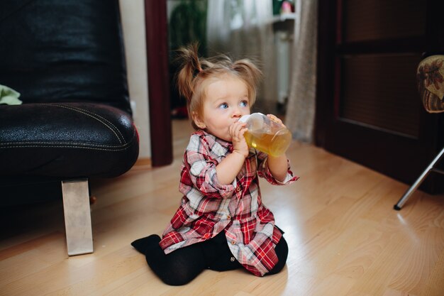 Menina que bebe de uma garrafa