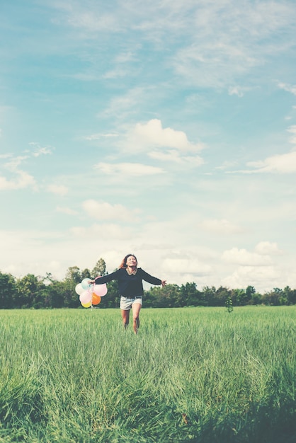 Menina que funciona no campo com balões