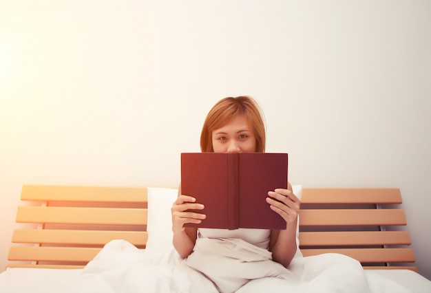 Menina que lê um livro em sua cama