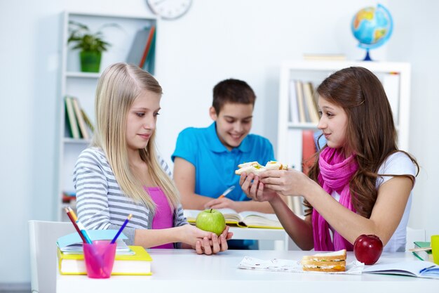 Menina que oferece sanduíche para sua amiga