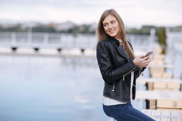 Menina que olha para trás com um telefone na mão