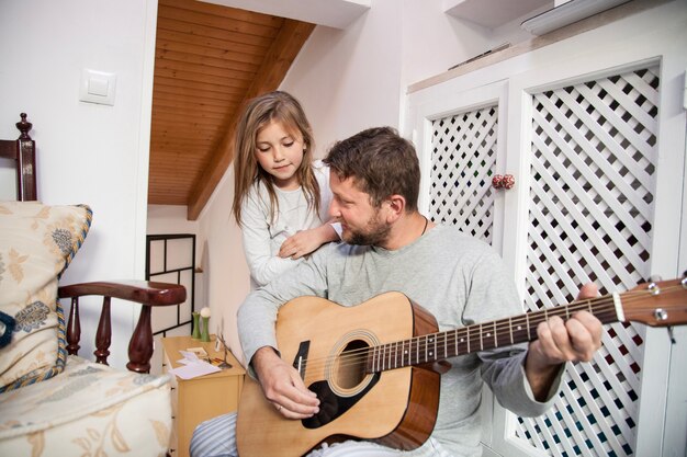 Menina que olha seu pai ao jogar a guitarra