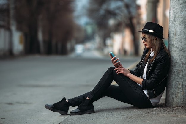 Menina que olha seu telefone celular sentado no chão