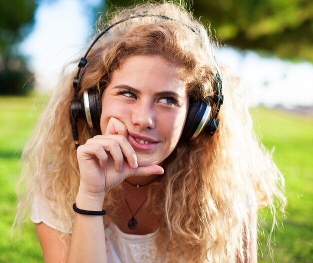 Menina que pensa ao ouvir música ao ar livre