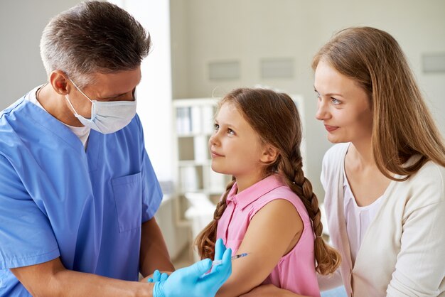 Menina que recebe a vacina no escritório médico