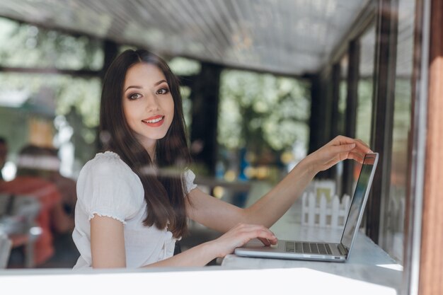 Menina que sorri com um laptop