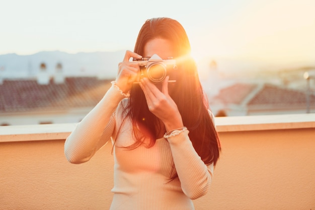 Menina que toma uma foto com sua câmera retro