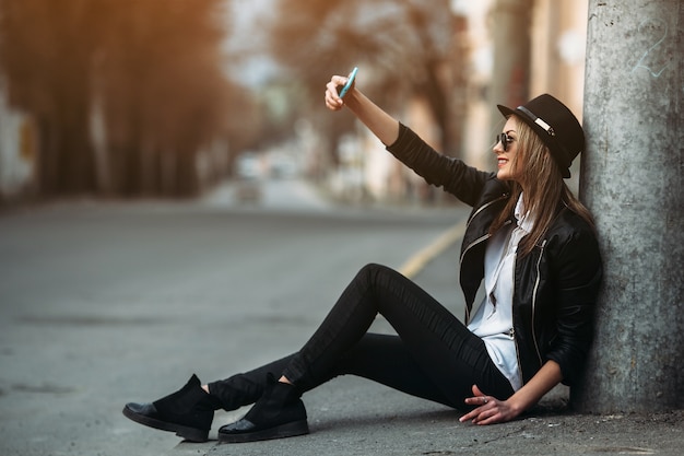 Menina que toma uma selfie sentado no chão