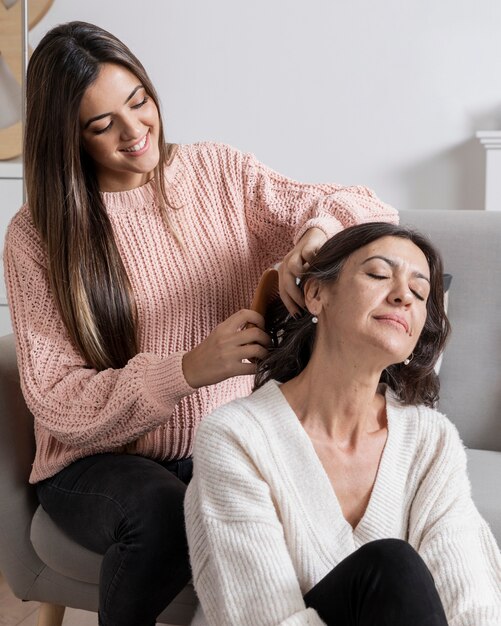 Menina que trança o cabelo da mãe