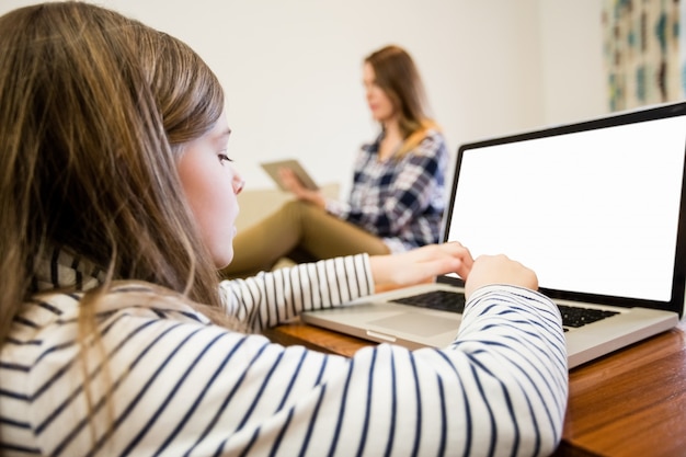 Menina que usa o laptop na sala de estar