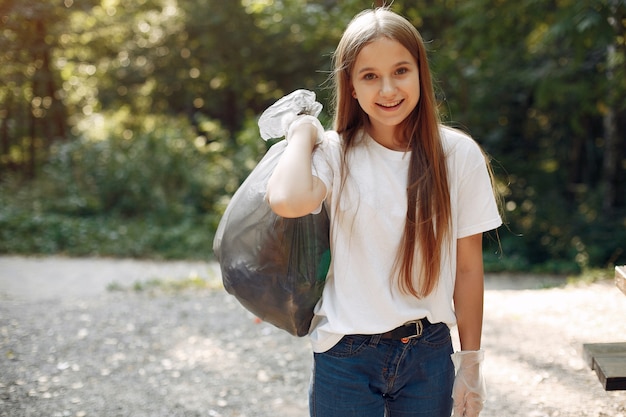 Menina recolhe lixo em sacos de lixo no parque