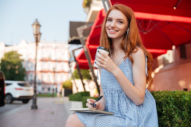 Menina ruiva alegre feliz em fones de ouvido