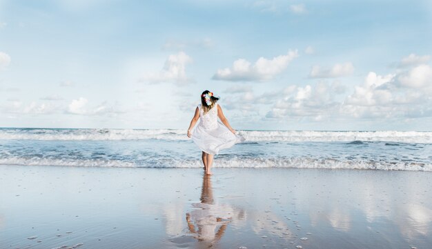 Menina saindo do mar vestindo roupas brancas