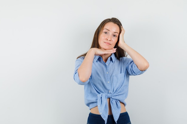 Menina segurando a mão sob o queixo em uma camisa azul, calça e linda