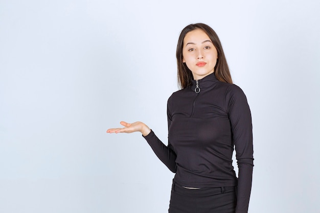 Menina segurando algo na mão e apresentando-o.