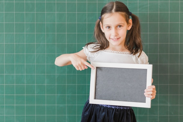 Foto grátis menina, segurando, e, apontar, em, chalkboard