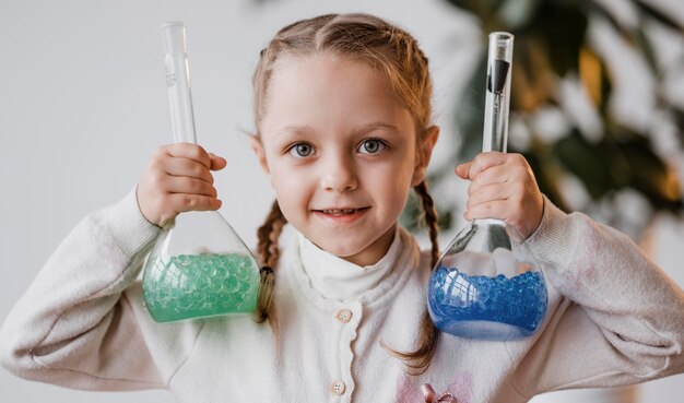 Menina segurando elementos químicos em recipientes