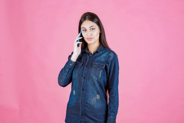 Menina segurando falando com seu smartphone azul