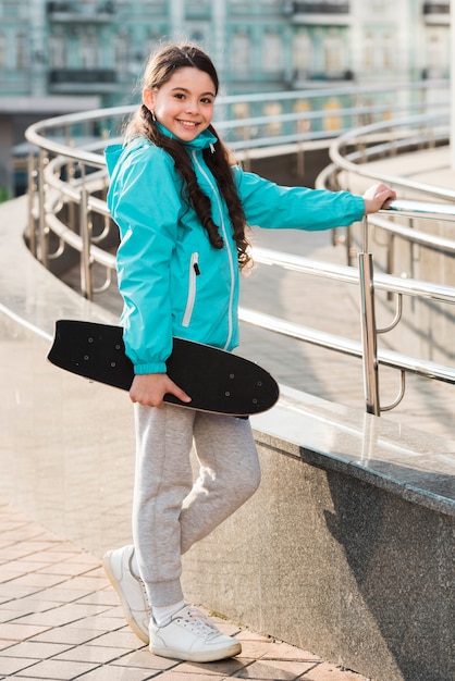 Menina, segurando na mão um skate