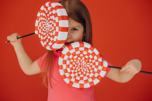 Foto grátis menina segurando pirulito grande isolado em fundo vermelho