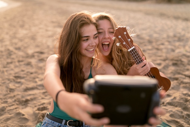 Menina, segurando, ukulele, levando, auto-retrato, de, câmera instantânea, em, praia