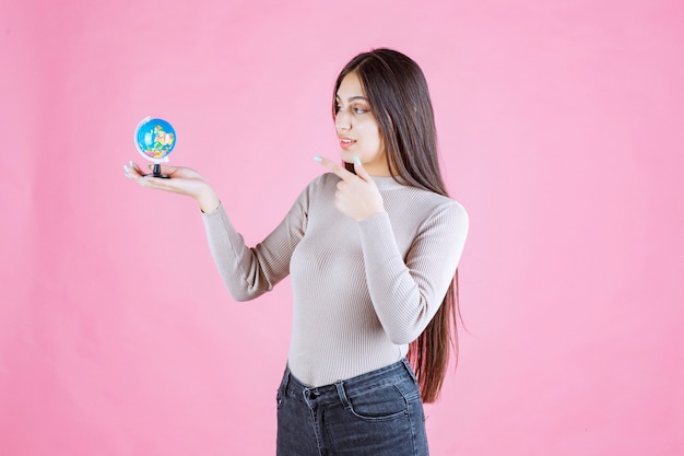 Menina segurando um mini globo e estudando-o atentamente