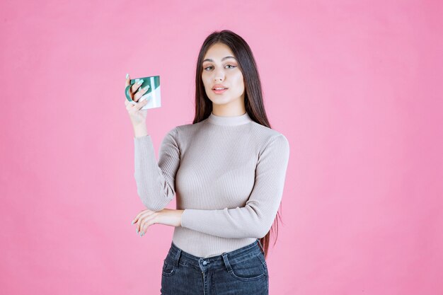 Menina segurando uma caneca de café verde e branca e se sentindo positiva