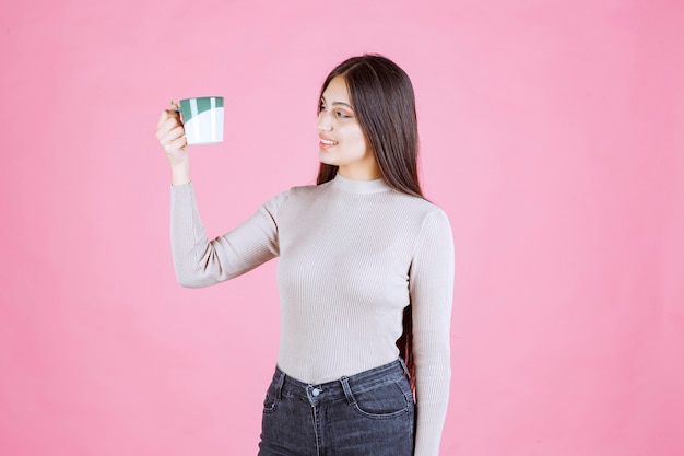 Menina segurando uma caneca de café verde e branca e se sentindo positiva