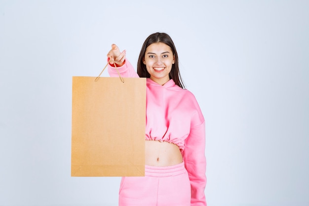Menina segurando uma sacola de compras de papelão e oferecendo ao cliente.