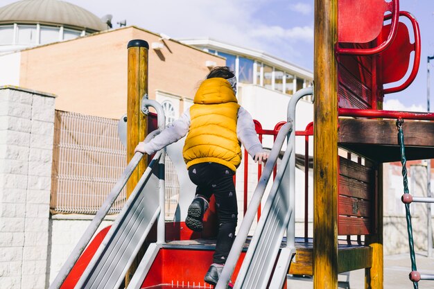 Menina sem rosto subindo no parque infantil