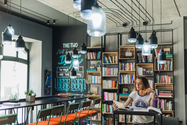 Foto grátis menina sentada à mesa, olhando caderno