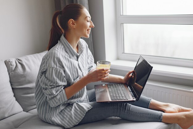 Menina sentada em casa e use o laptop