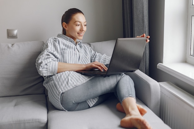 Menina sentada em casa e use o laptop